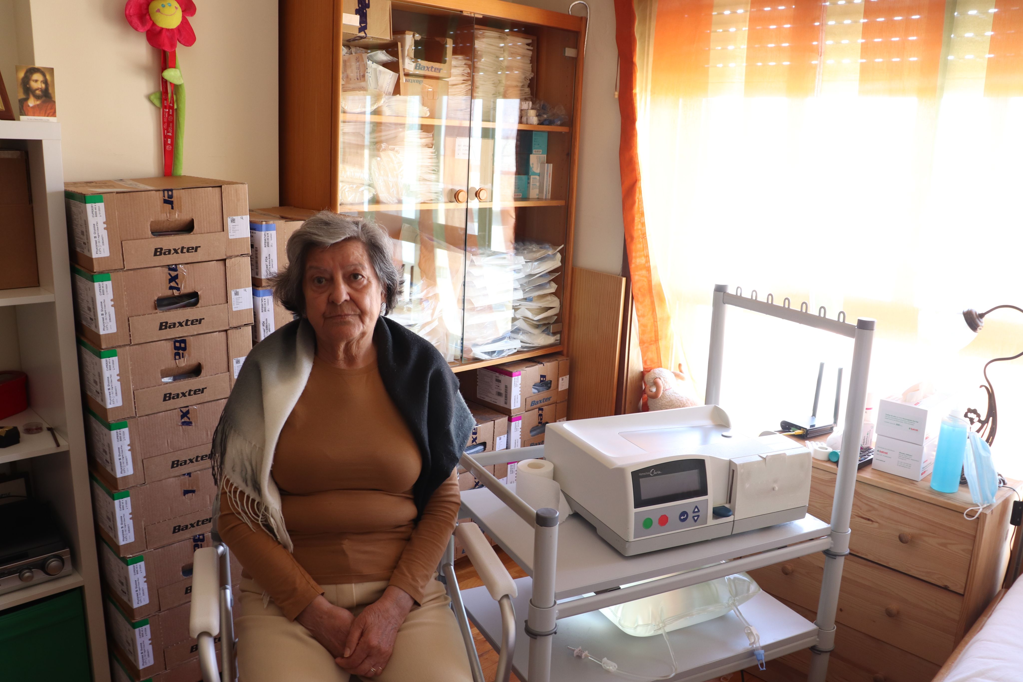 Lídia Alves está sentada no quarto ao lado da máquina de hemodiálise